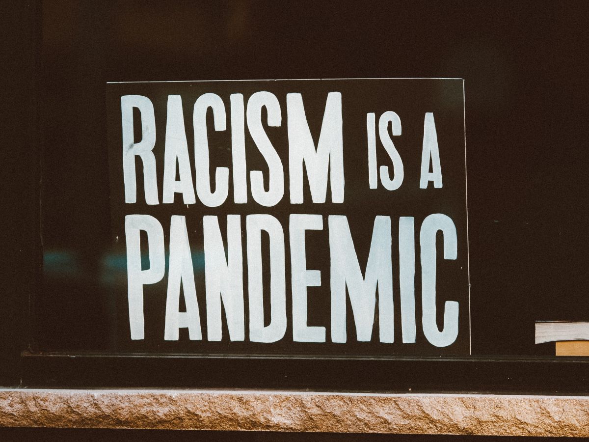 a sign inside a window that reads 'Racism is a Pandemic'