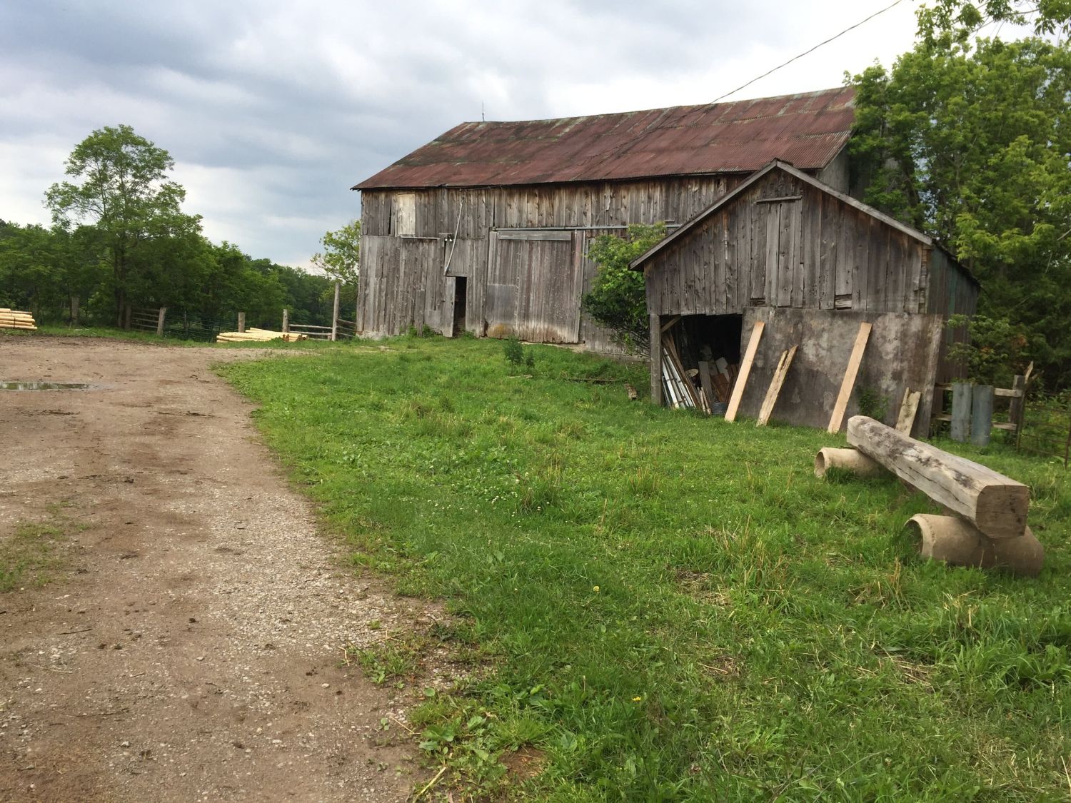a barn and an outbuilding, with a dirt road leading to them
