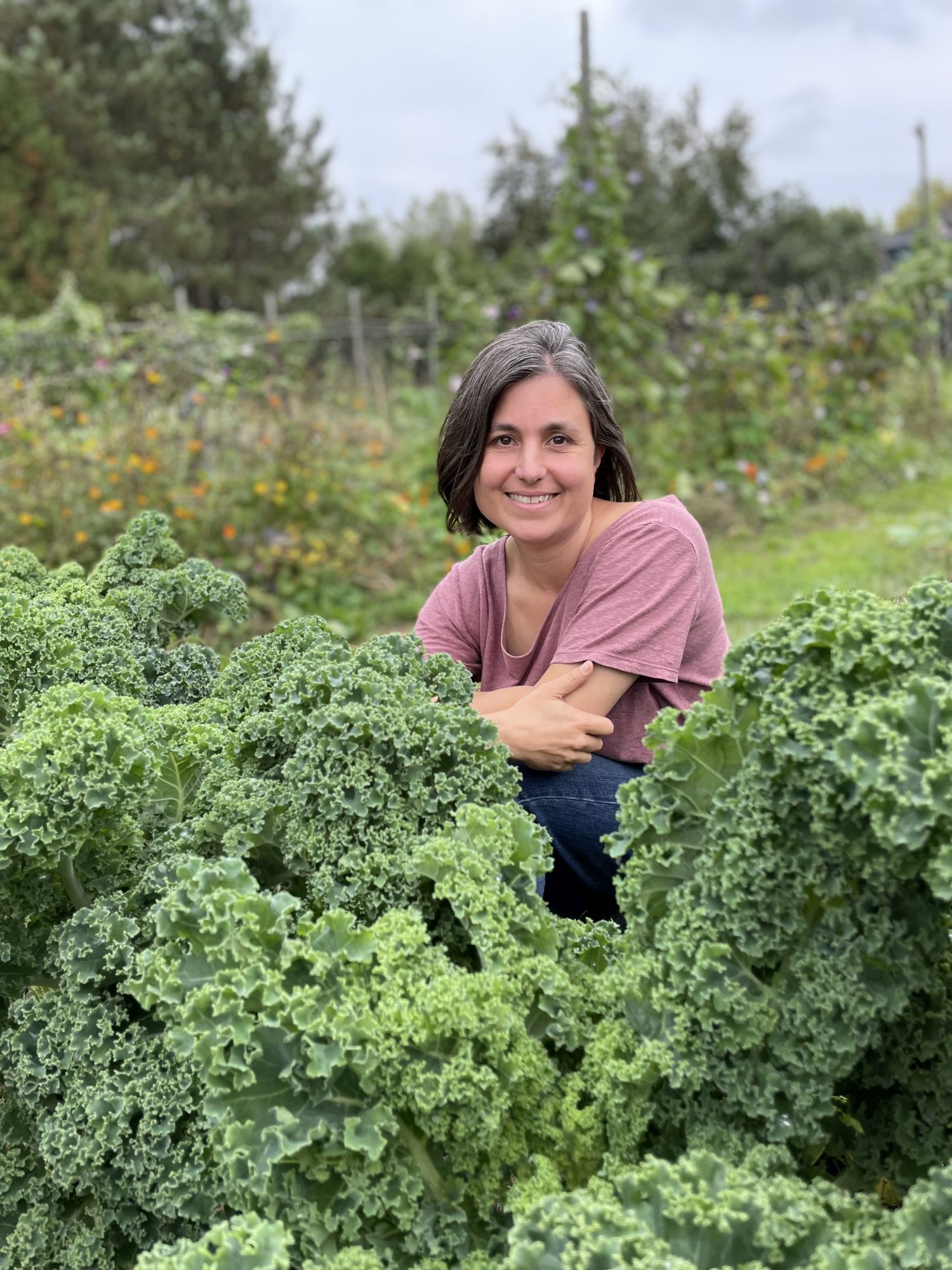 Sarah Elton, behind some kale growing in a garden