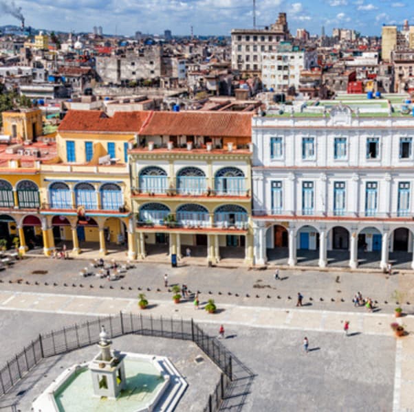 An open-air courtyard with an ornate fountain in the centre. The courtyard is surrounded by low-rise buildings.