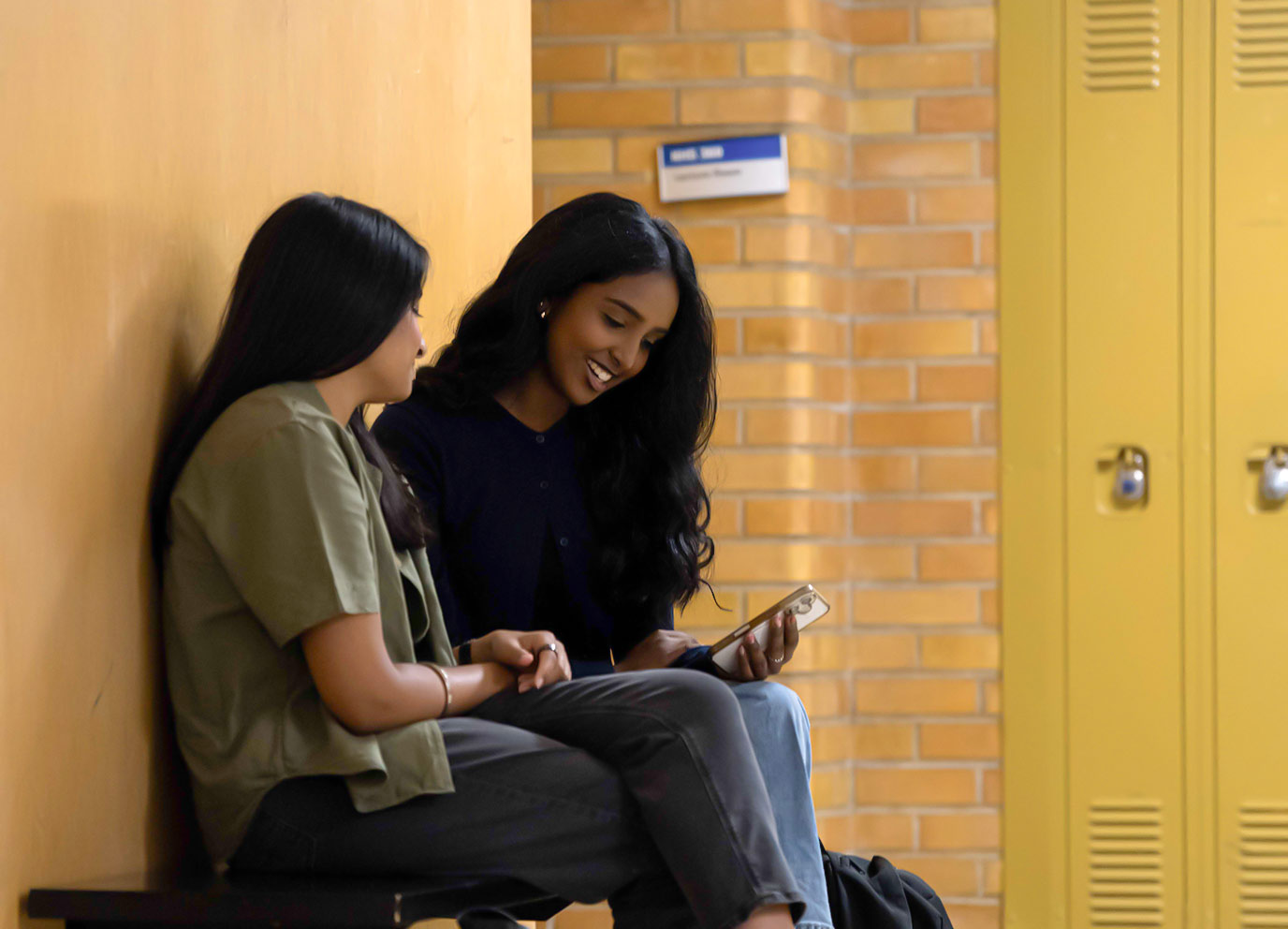 Two students sitting in SLC checking a phone for budgeting tips