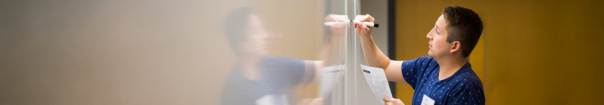 Student writes on a whiteboard with a marker