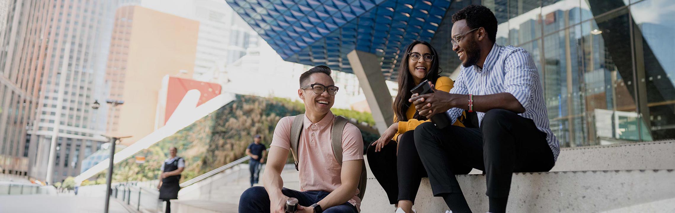 Three students sit on the steps of TMU campus