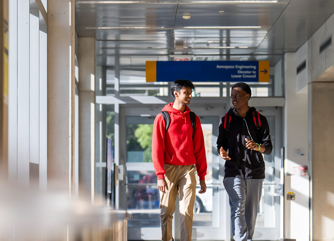 Two students talking while they walk down TMU hallway