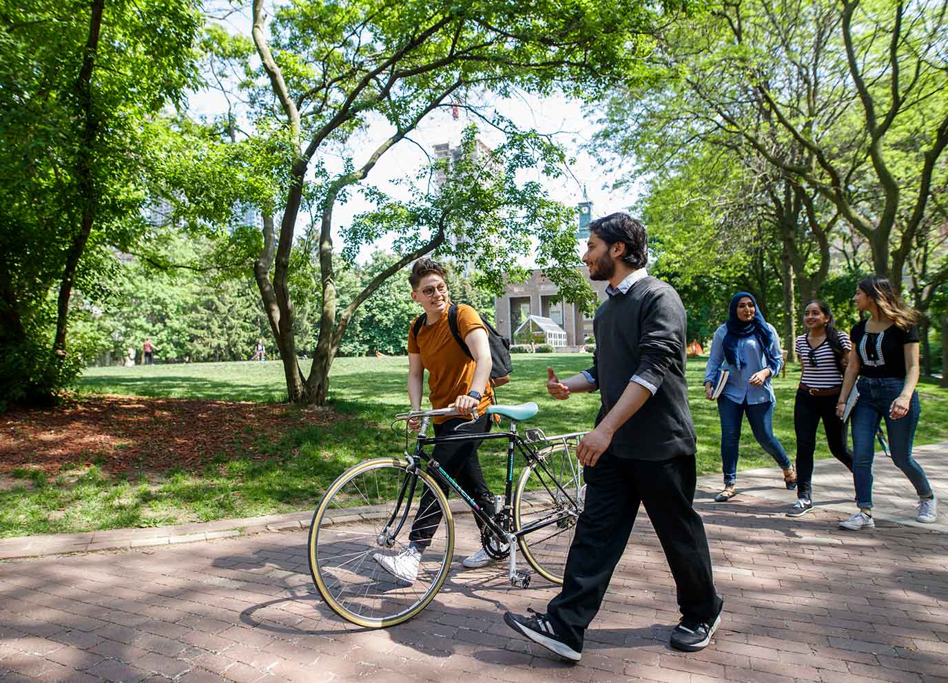 Students walking on campus as one walks their bicycle