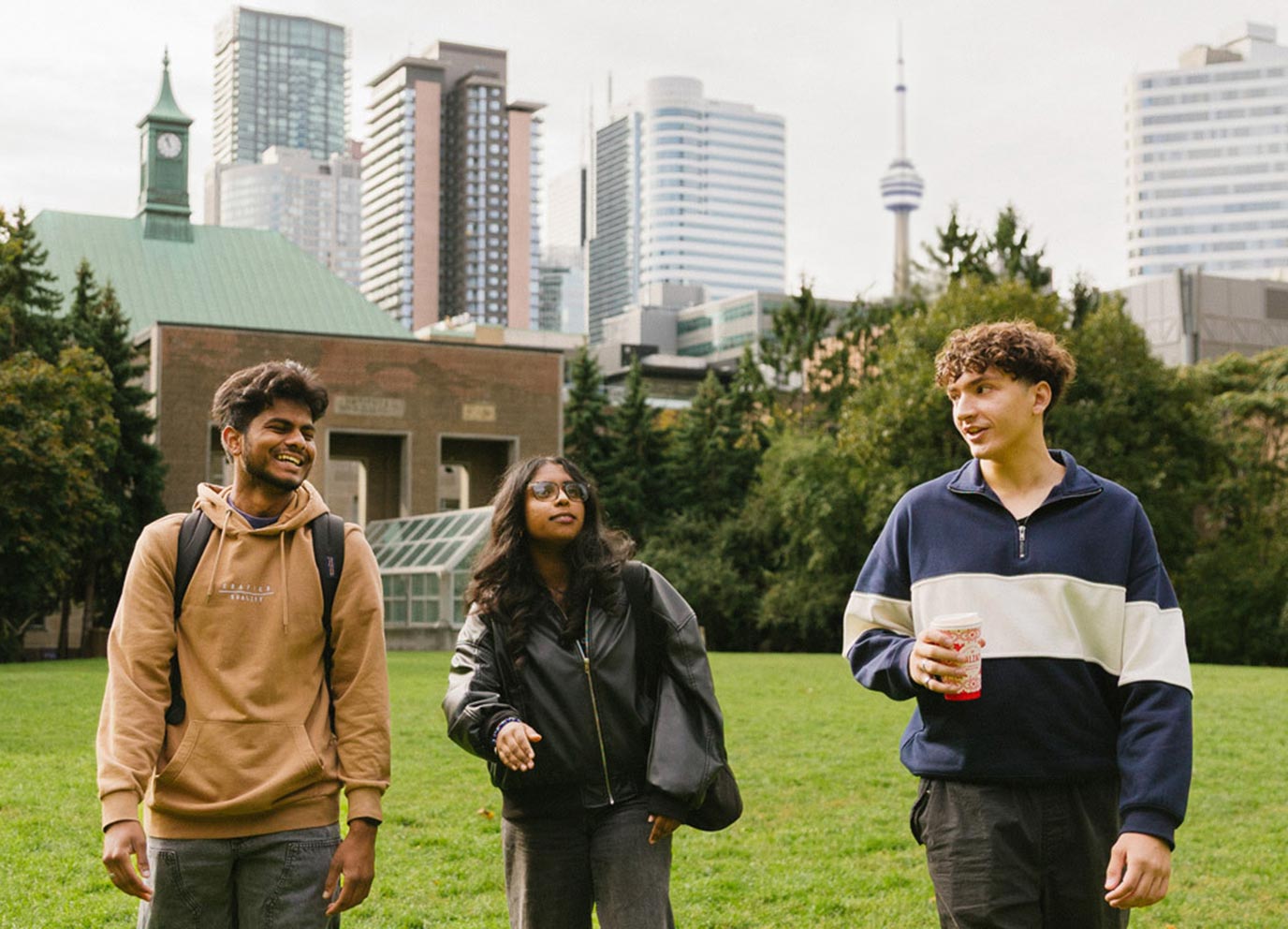 Three students walking outside of TMU campus with Toronto scenery and CN tower in the background 