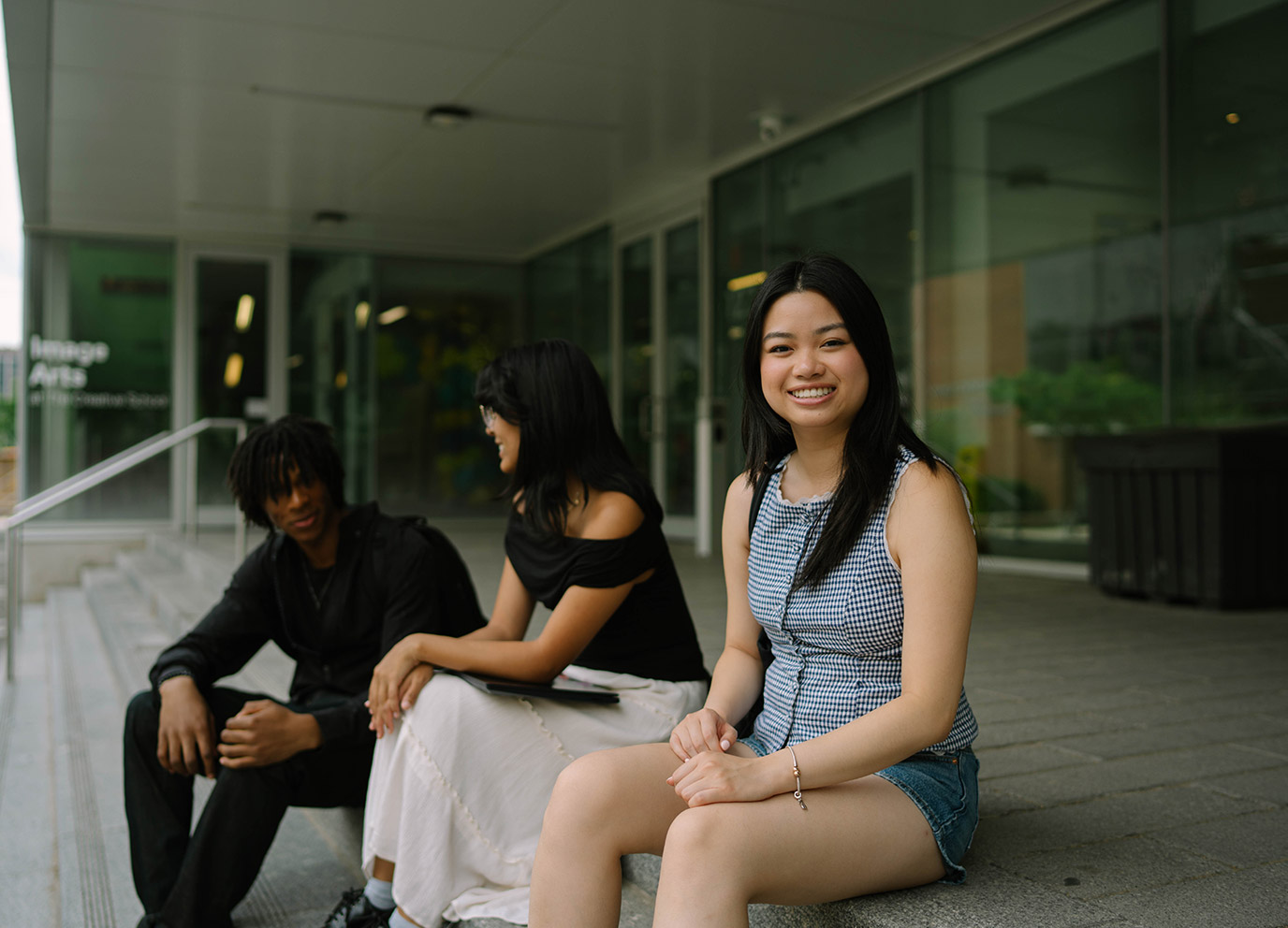 Students sitting on SLC steps on TMU campus, one student smiling towards the camera