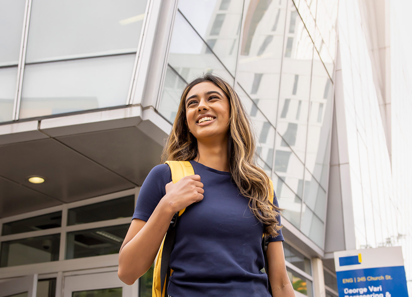 Student stands in front of Student Learning Centre at TMU