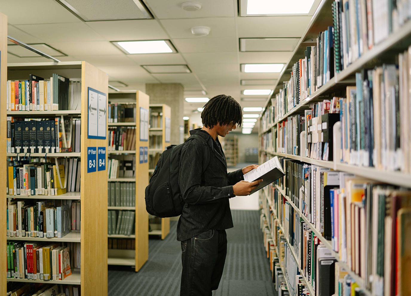 TMU student in a library reading a book that he pulled off the shelf