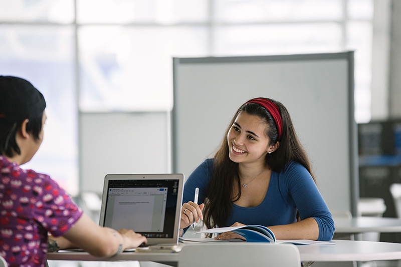 Two students sitting at a table with a laptop