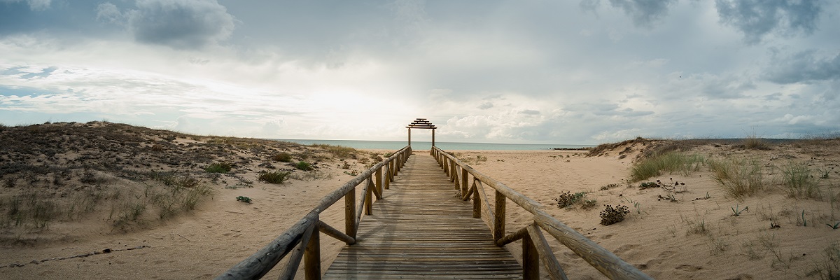 Wooden long platform leading to the beach under the cloudy sky