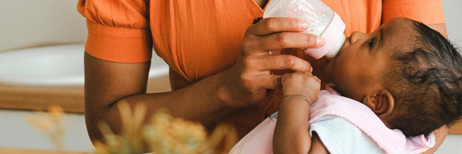 An infant being bottle fed in a quiet space.