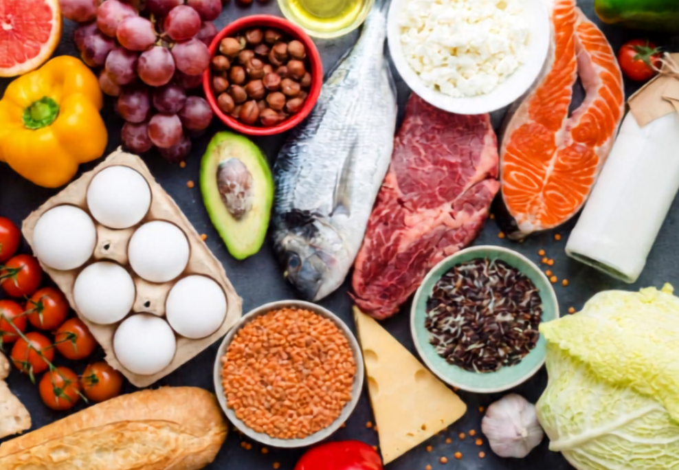 nutritious food such as eggs, tomatoes, grapes, peppers, salmon and more laid out on couter.