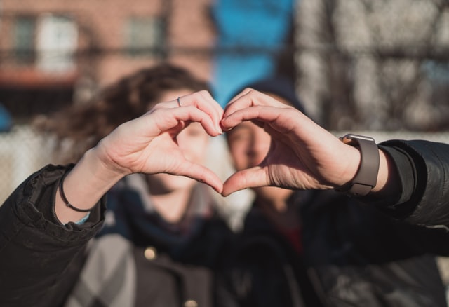 Two people holding up their hands to make a heart