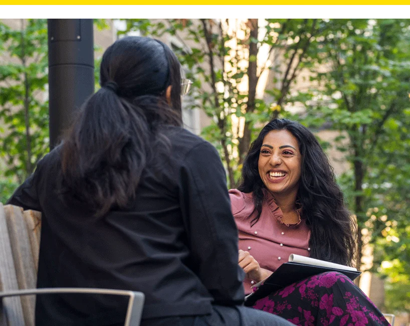 a student and a counsellor smiling together on a bench