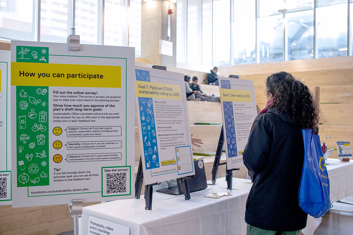 A student looks at display panels that provide an overview of the Sustainability Action Plan and each of its three long-term goals.