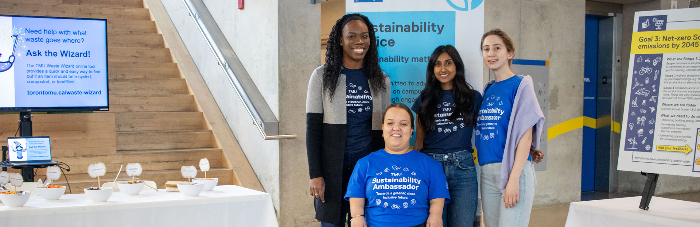 Four sustainability ambassadors and full-time staff standing in the SLC atrium.