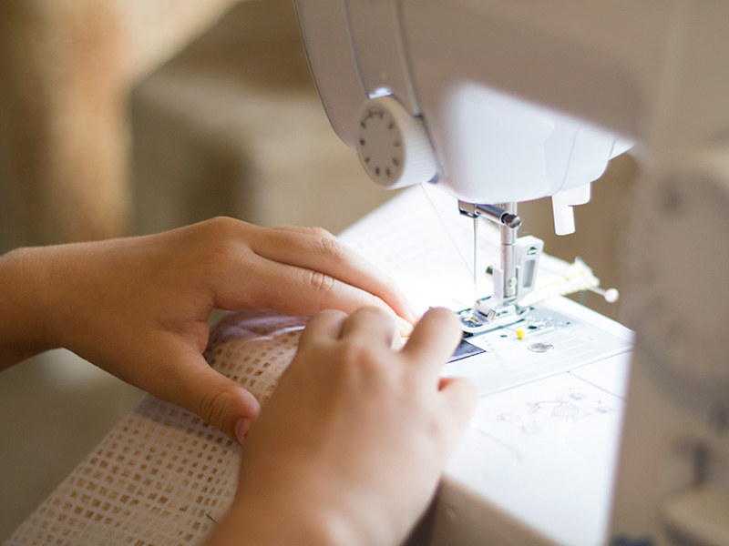 Hands moving fabric through a sewing machine.