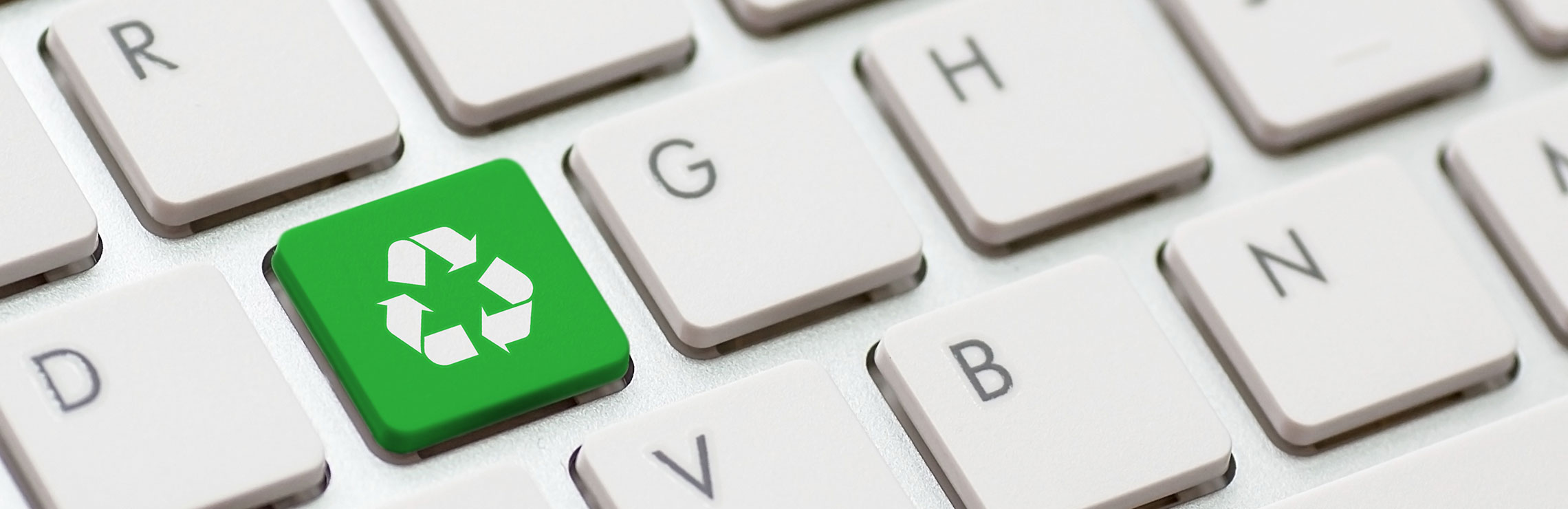 A computer keyboard where one of the keys is a green recycling logo instead of a letter or number.