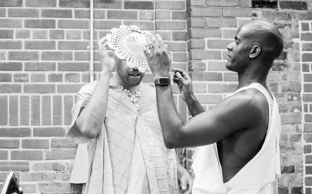 Mic Carter placing a hat on a model