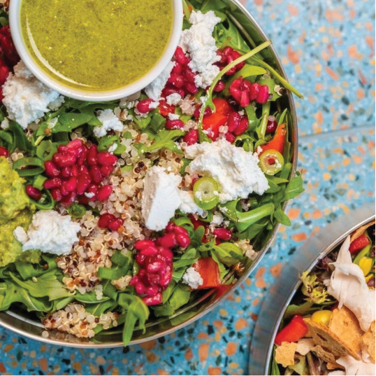 A close up shot of food in a reusable container placed on a blue decorative table.