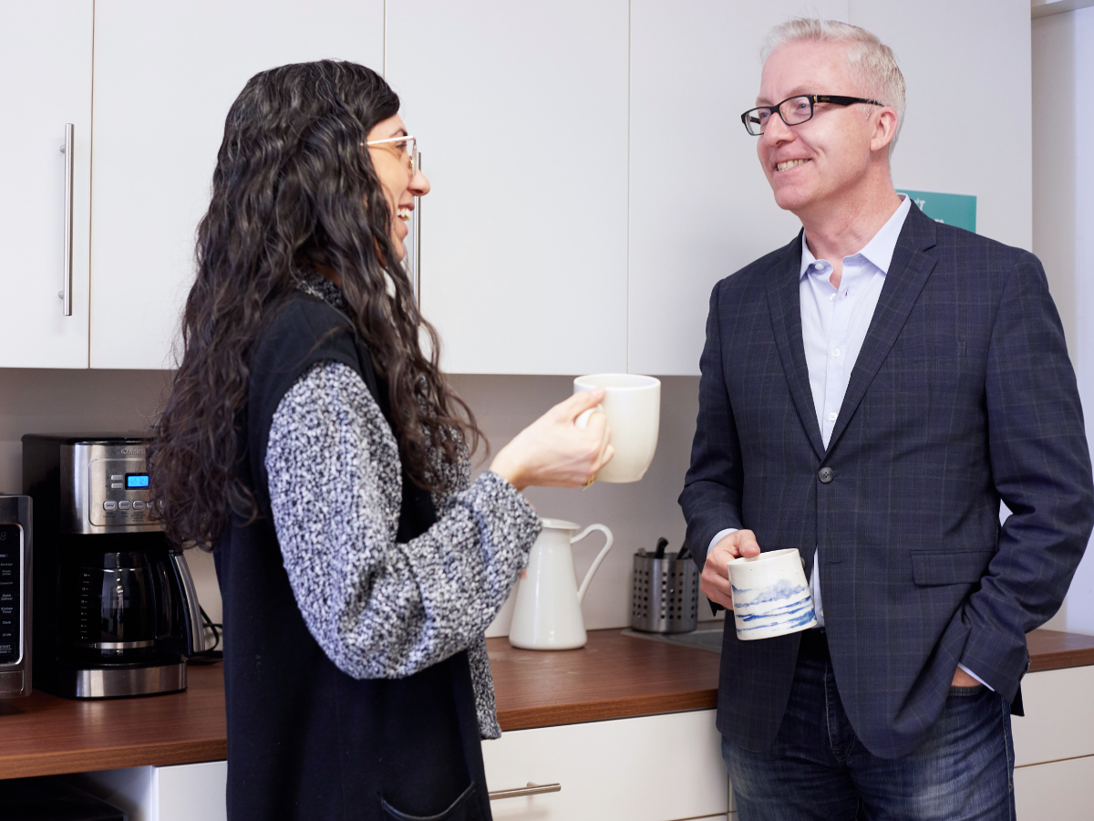 Alex Gill speaking to an entrepreneur, both holding coffee mugs