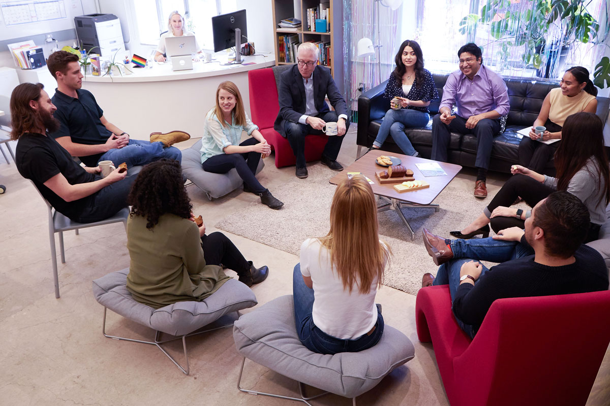 Group of people sitting in a circle drinking coffee and talking