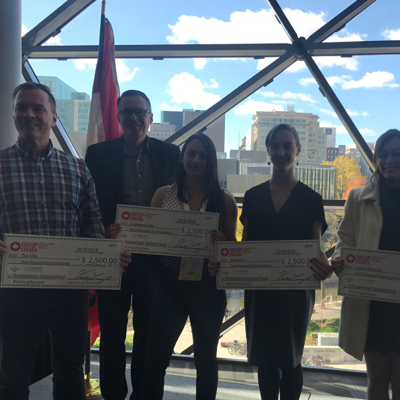 men and women holding two thousand five hundred dollar cheques