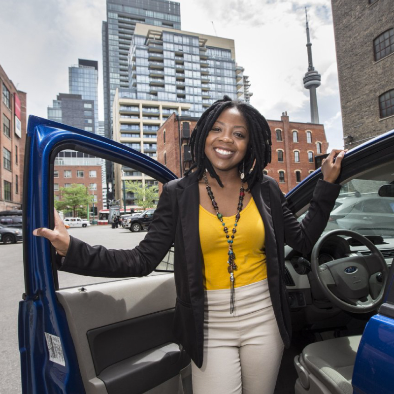 Founder Aisha standing out of a car and smiling