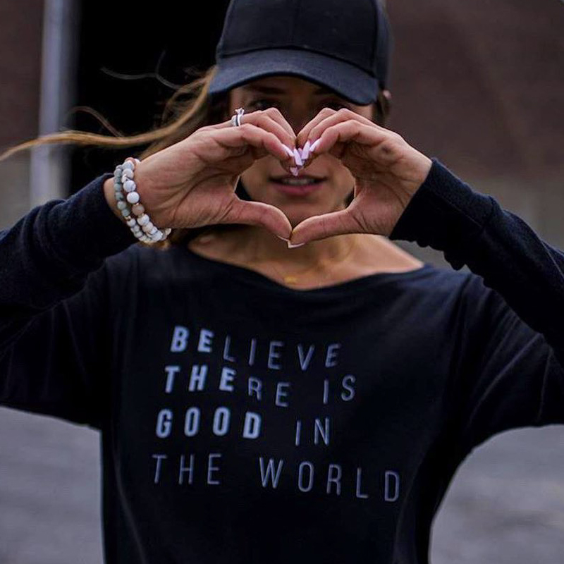 Woman wearing a shirt and making a heart shape with her hands