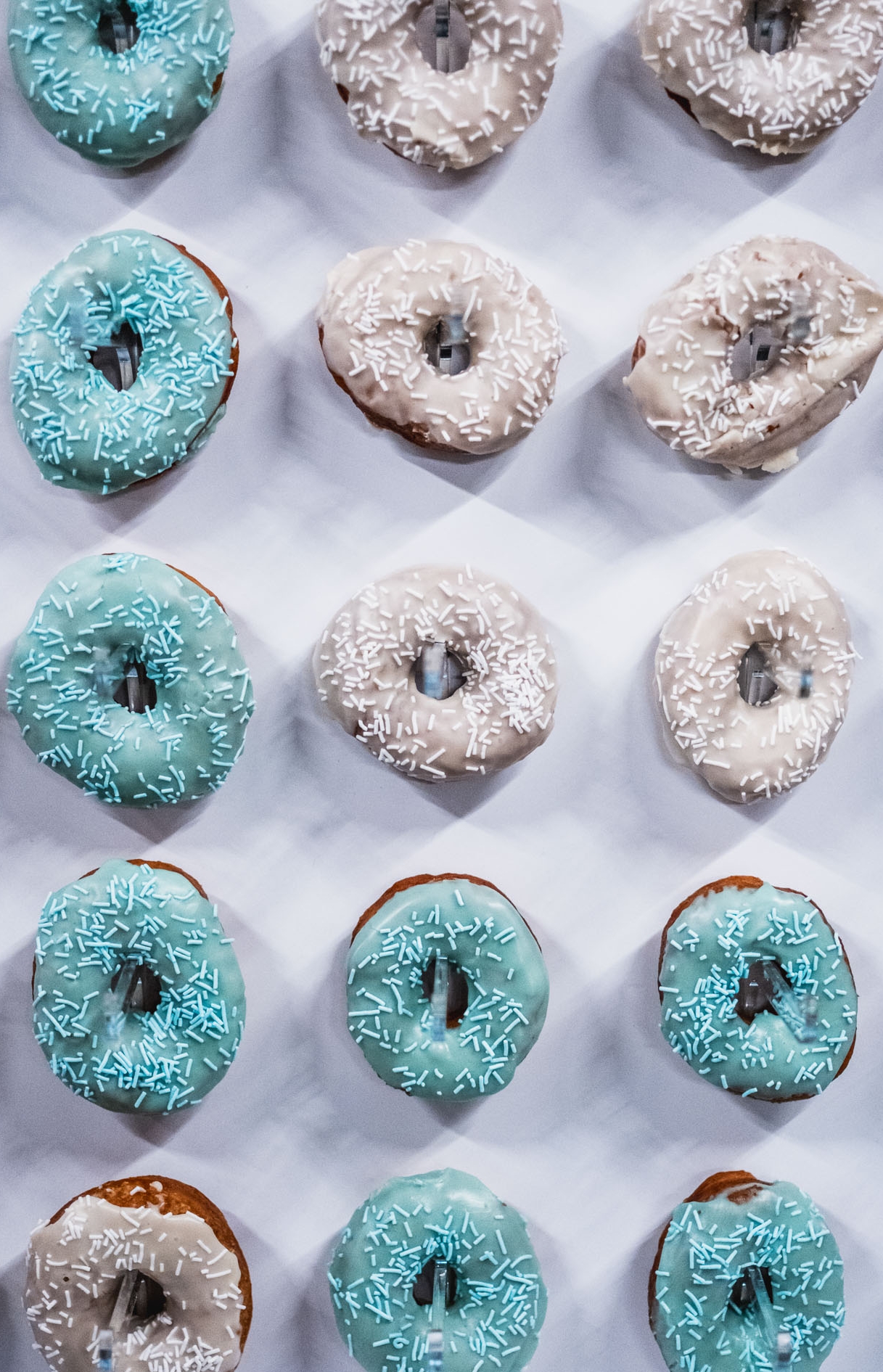 An overhead picture of blue and white donuts arranged in vertical rows