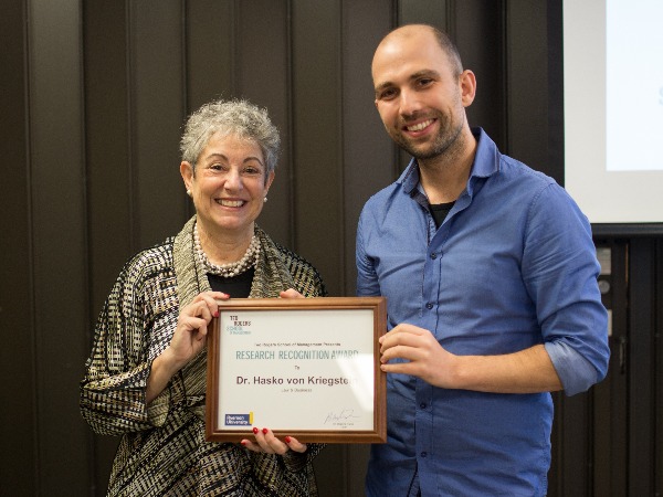 Dr Hasko Von Kriegstein reciveing an award from Dean Daphne Taras