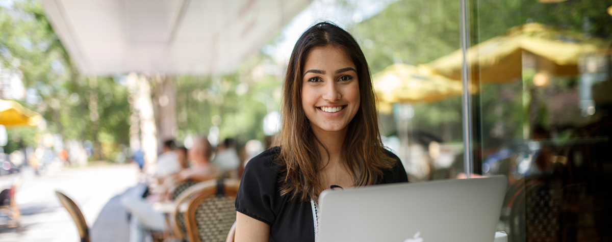 A girl smiling at the camera while working on her laptop