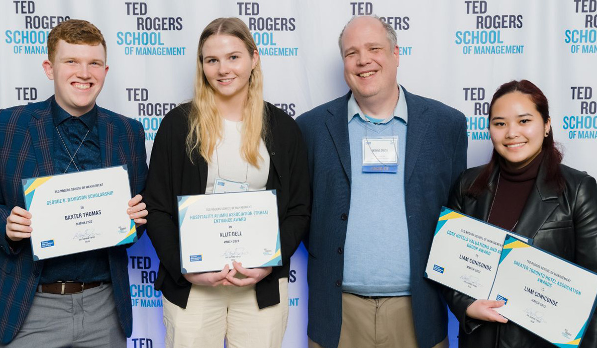 Professor Wayne Smith with three HTM students holding award certificates
