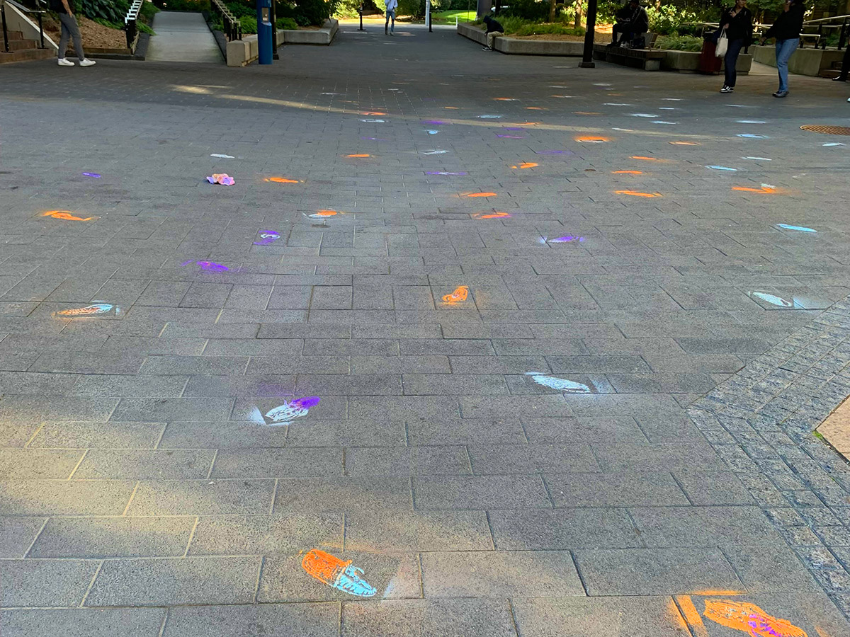 Stenciled moccasin shoes painted on the pavement scattered on TMU campus streets for the The Moccasin Identifier project