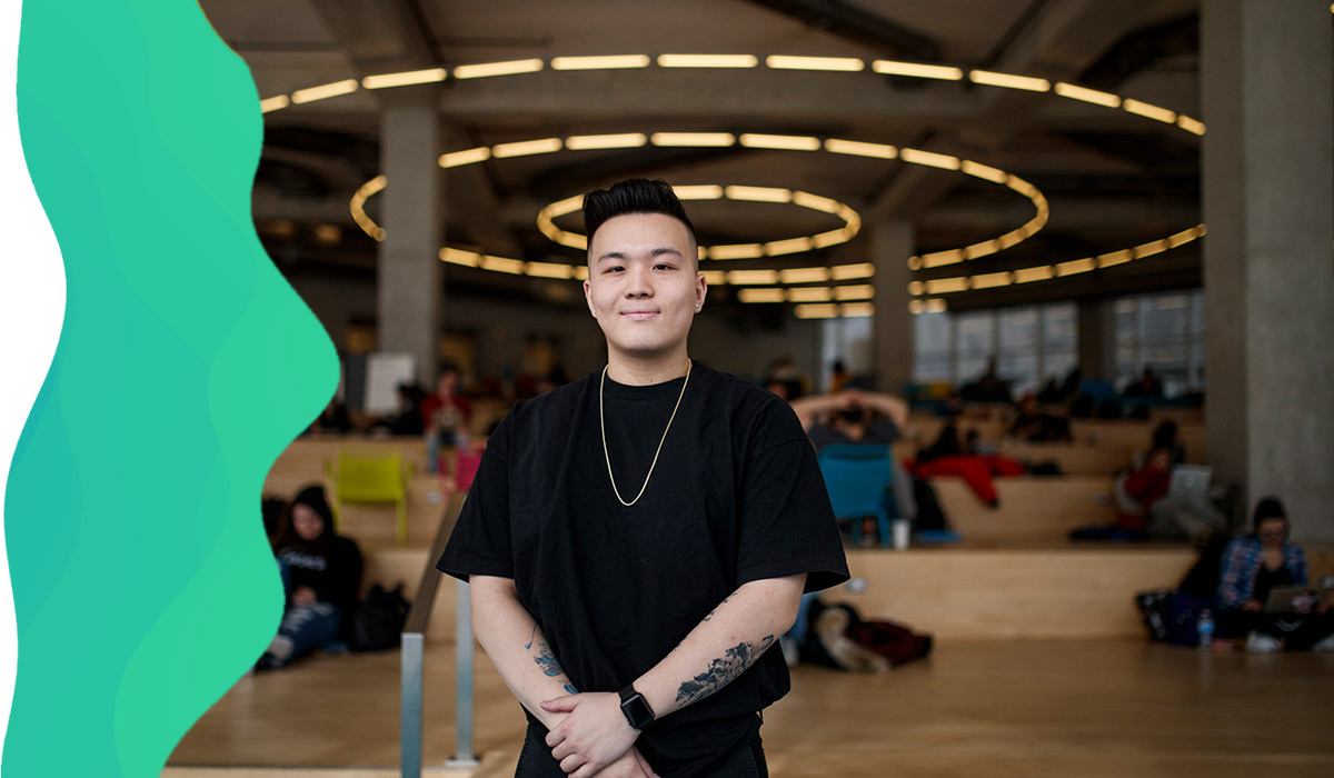 Student with crossed arms smiling at the SLC building