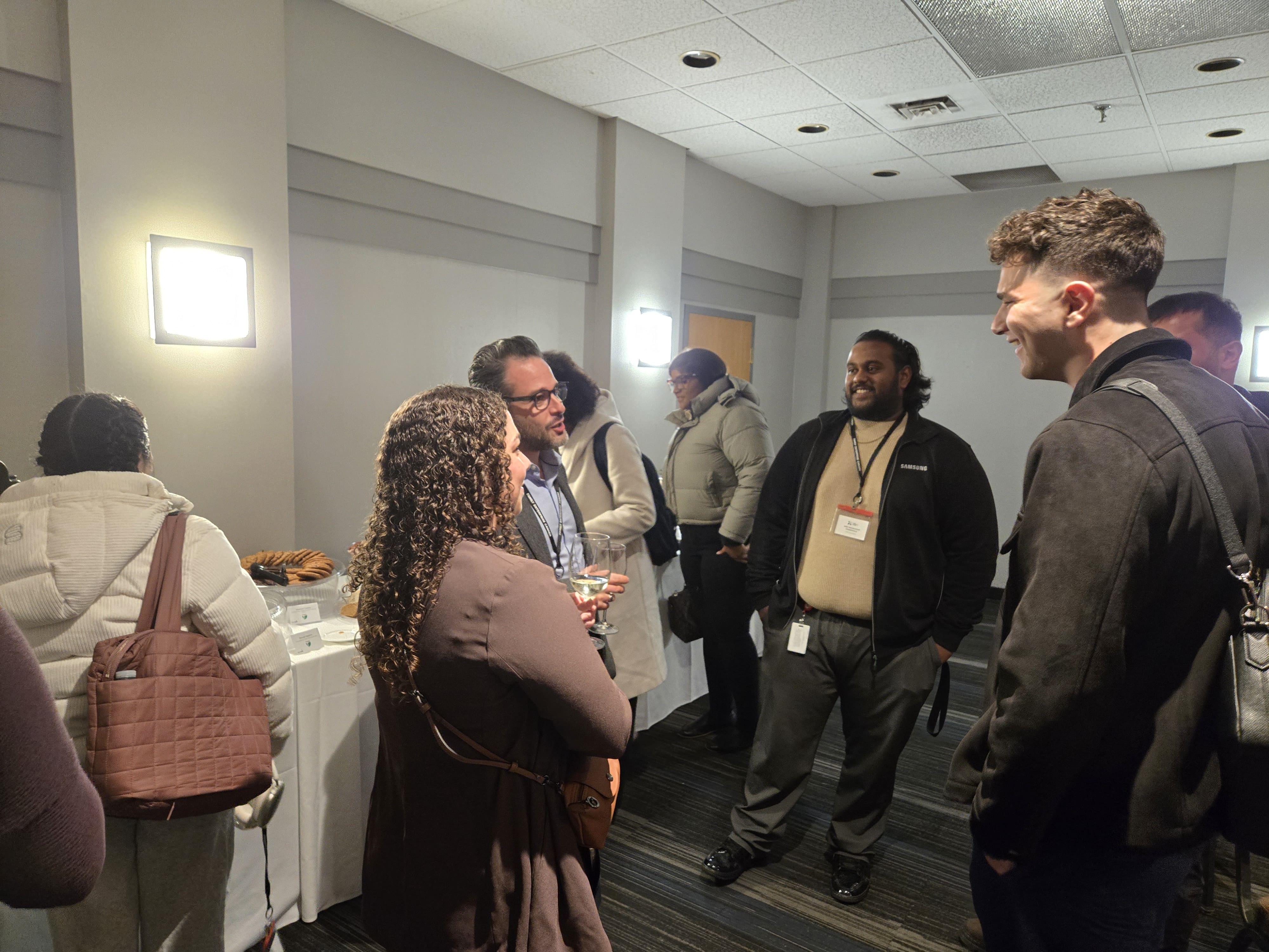 Guests chatting in a small group near the refreshment table during the networking session.