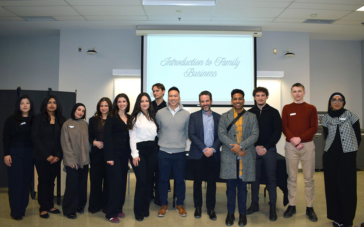 Professor Francesco Barbera with a diverse group of twelve FBSA students stands smiling in front of a projection screen that reads "Introduction to Family Business." They display a welcoming and professional tone.