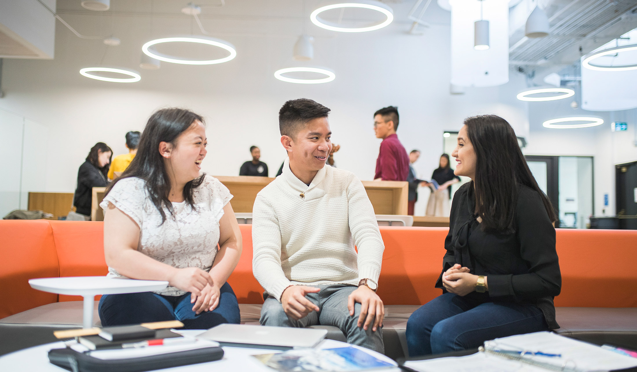 Three students discussing while sitting in the SLC area