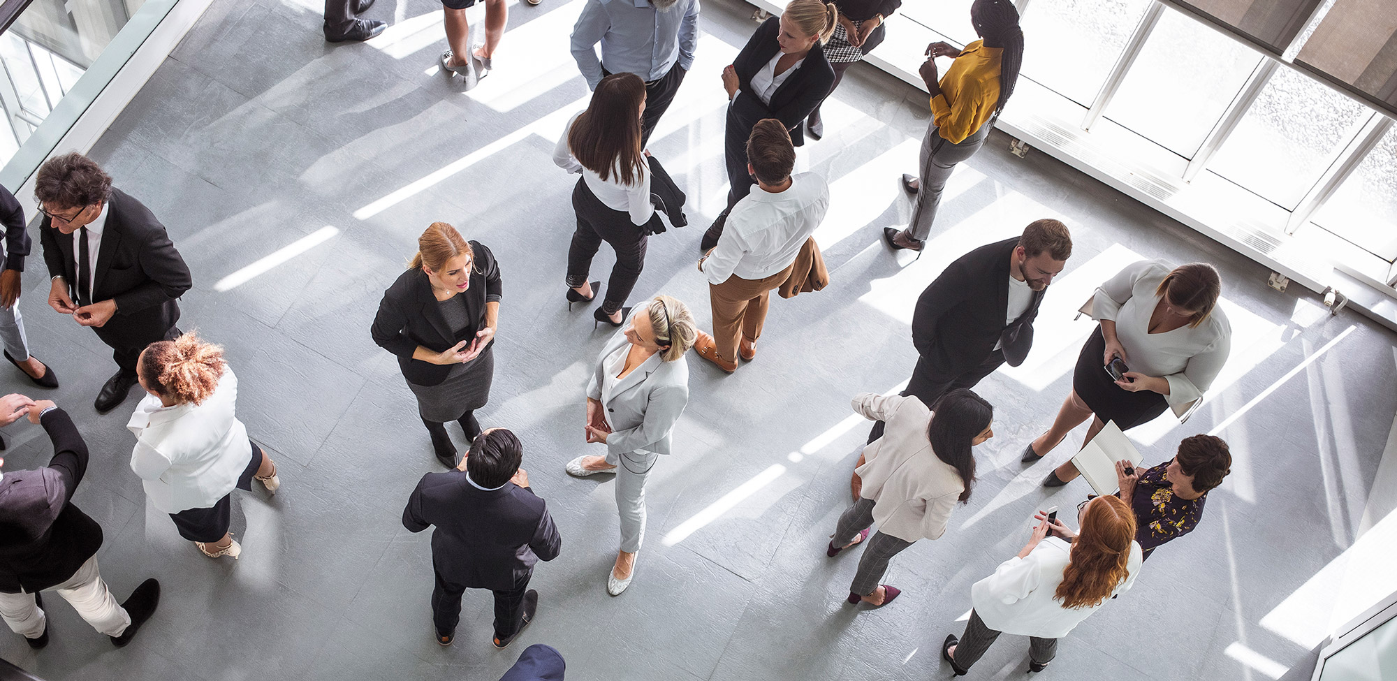 Diverse business professionals engaging at a conference event, dressed in formal business attire, networking and discussing ideas