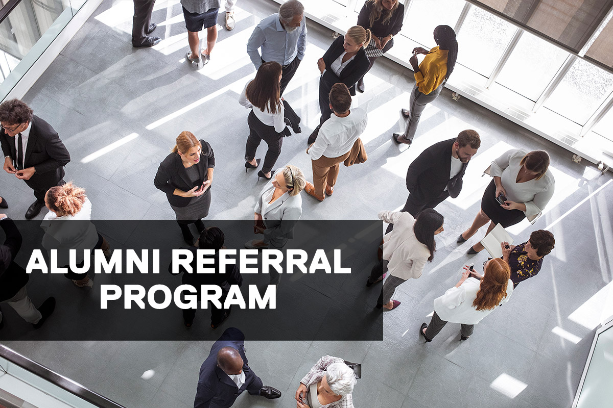 Diverse business professionals engaging at a conference event, dressed in formal business attire, networking and discussing ideas. Title over image: Alumni Referral Program.