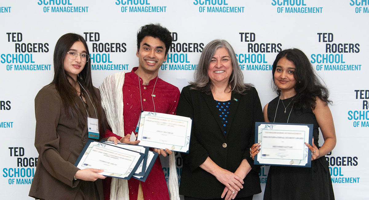 Dean Cynthia Holmes with three students holding the award certificates 