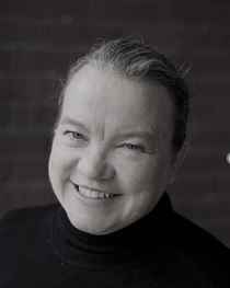 Carol Greenwood's headshot. Carol is turned to the side and smiling at the camera.