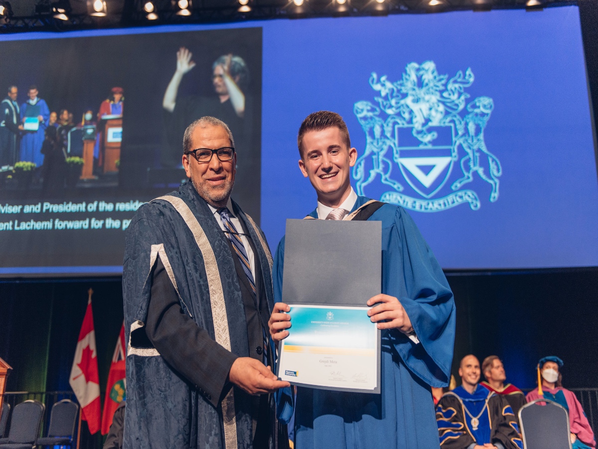 President Mohamed Lachemi, and student Grejdi Meta receiving his certificate