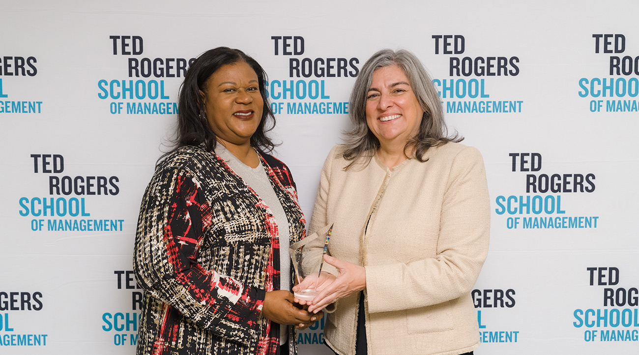 Dean Cynthia Holmes presenting award to an alumna at the Alumni Achievement Awards, October 2024