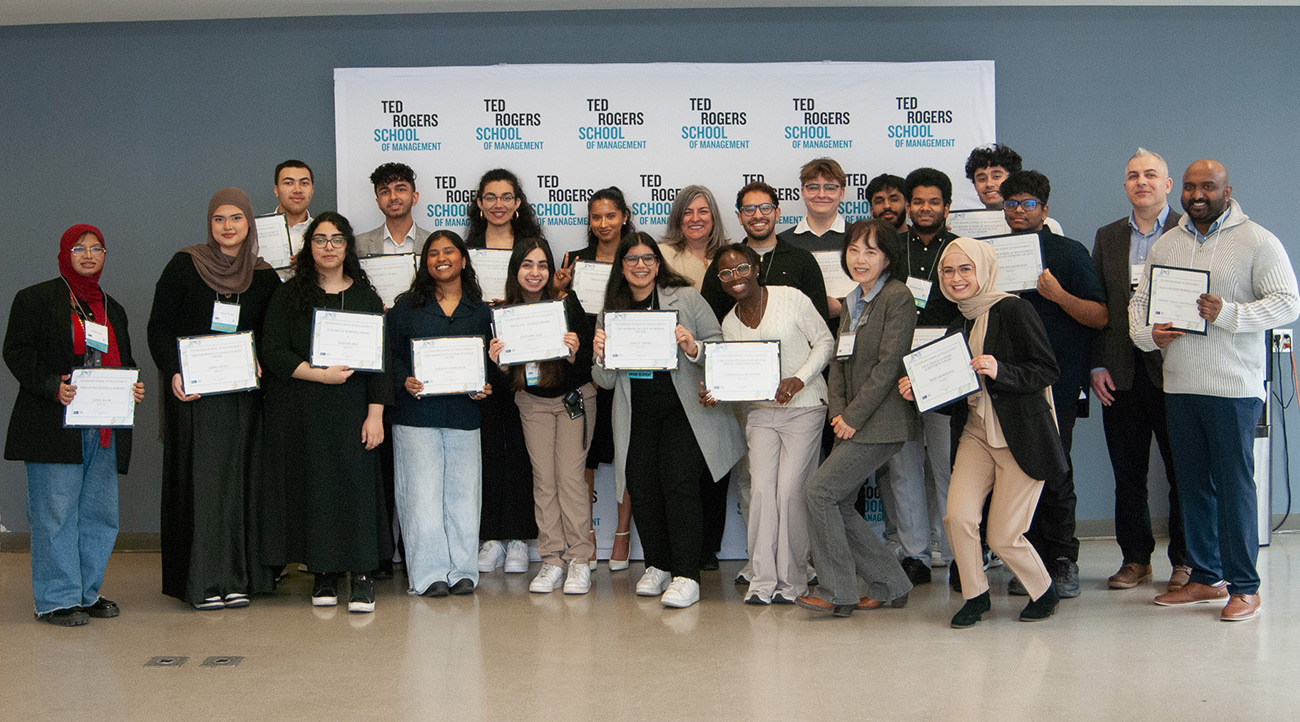 Dean Cynthia Holmes with a large group of students holding their award certificates and smiling at the Student Award Breakfast Celebrations, April 2025