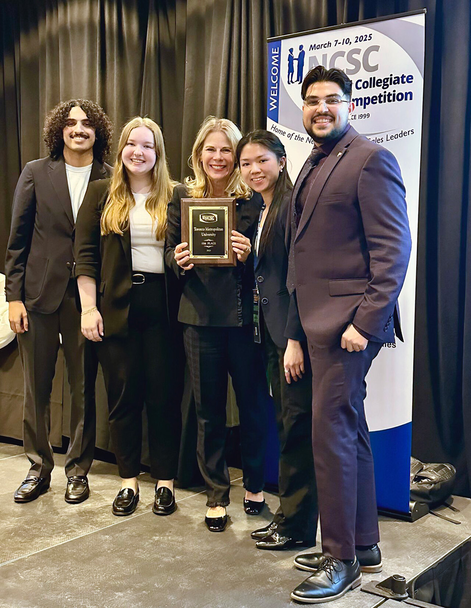 Professor Karen Peesker holding award surrounded by student competitors from Sales Competition event