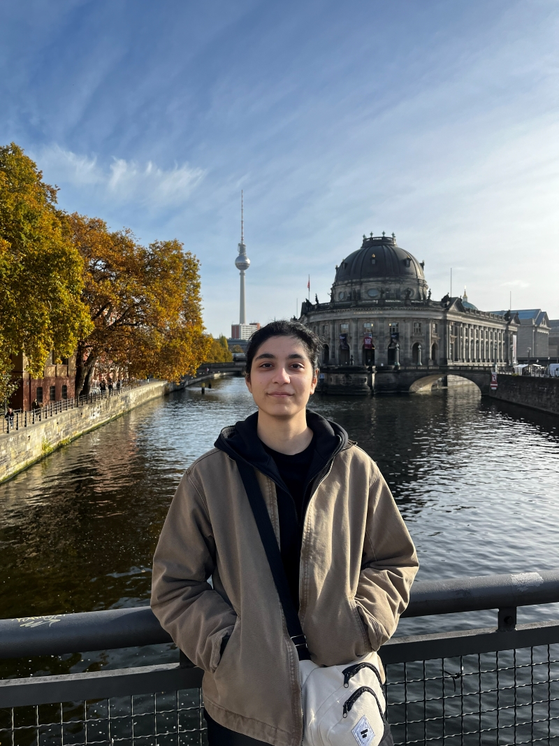 student posing for a photo in front of a canal and building and germany