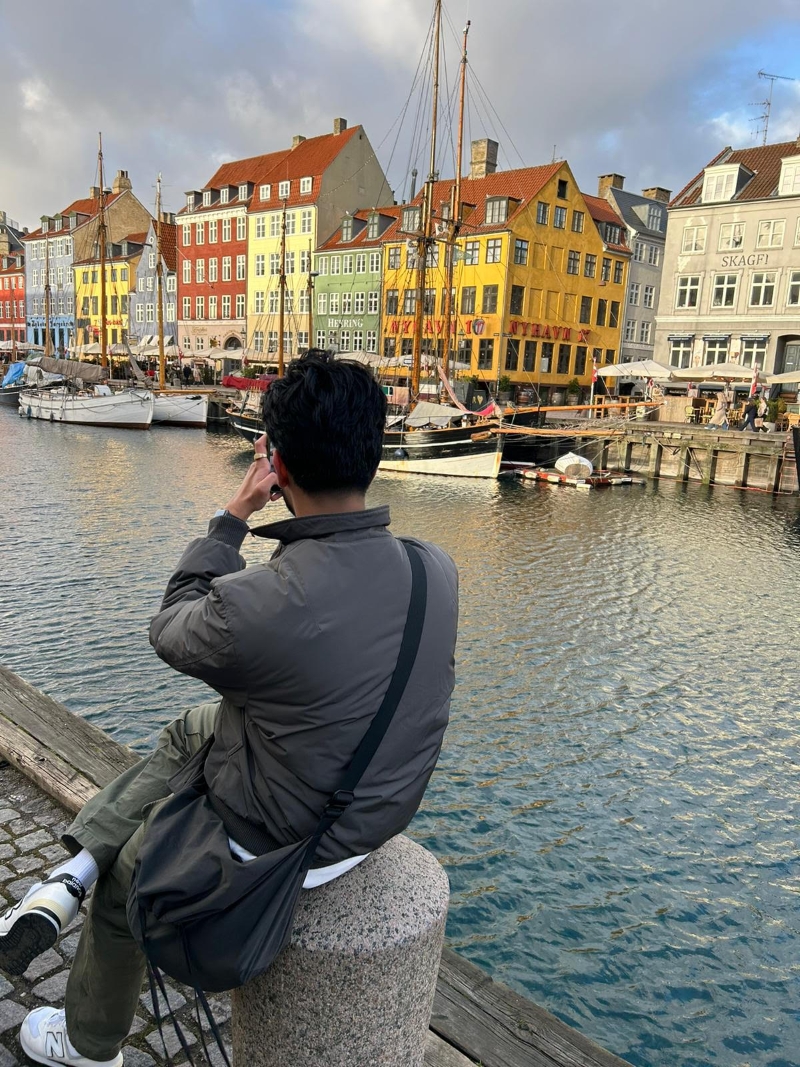 student taking picture of colorful vuildings over canal in denmark