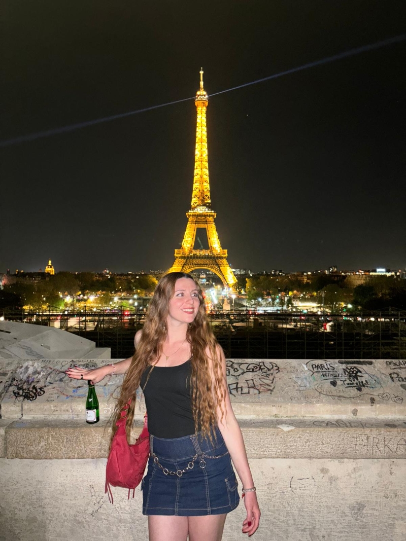 student posing in front of the eiffel tower at night